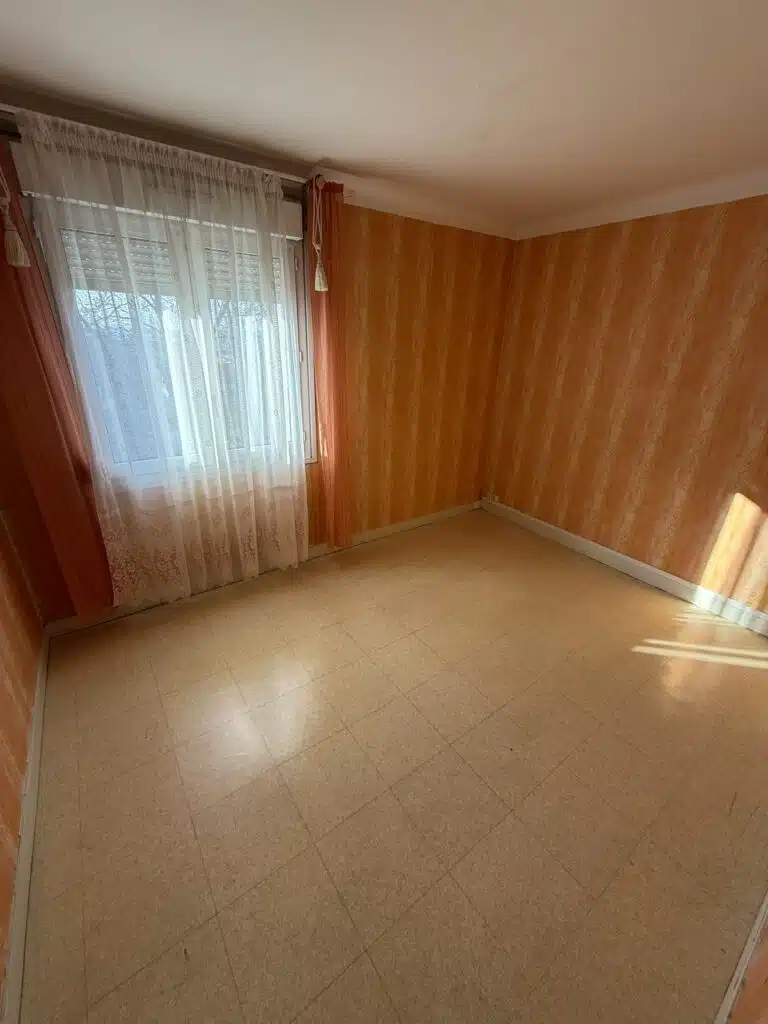 pièce vide avec tapisserie rose et volets ouverts