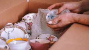 Zoom sur de la vaisselle en porcelaine soigneusement emballée dans du papier bulle avant d'être mise en carton